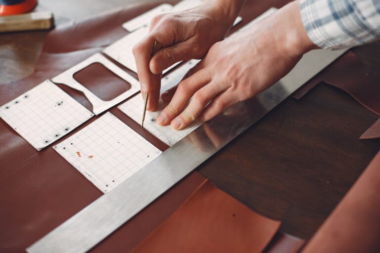 Anonymous artisan cutting leather strip in workshop