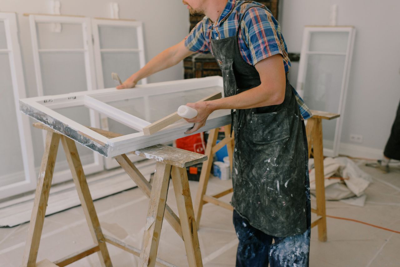A skilled craftsman repairing a window frame indoors using tools and expertise.