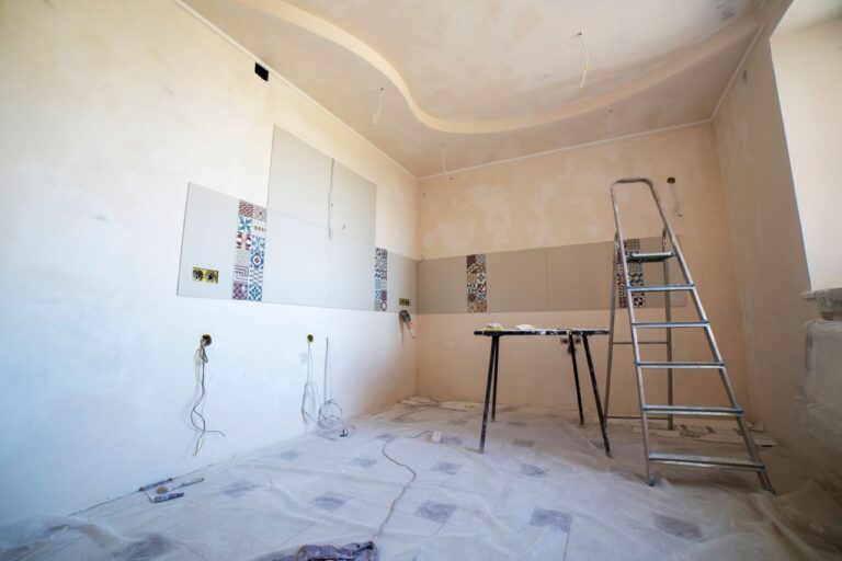 Interior view of a room under renovation with paint, tiles, and tools