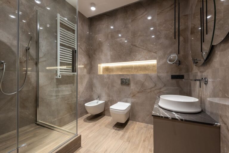 Elegant marble bathroom featuring a round mirror and stylish fixtures for contemporary living.